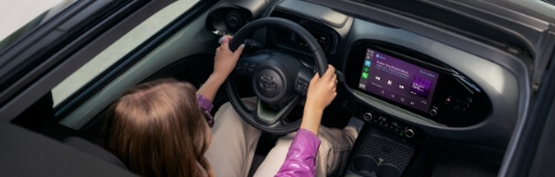 Kobieta w rózowej bluzce prowadzi nowoczesną Toyotę